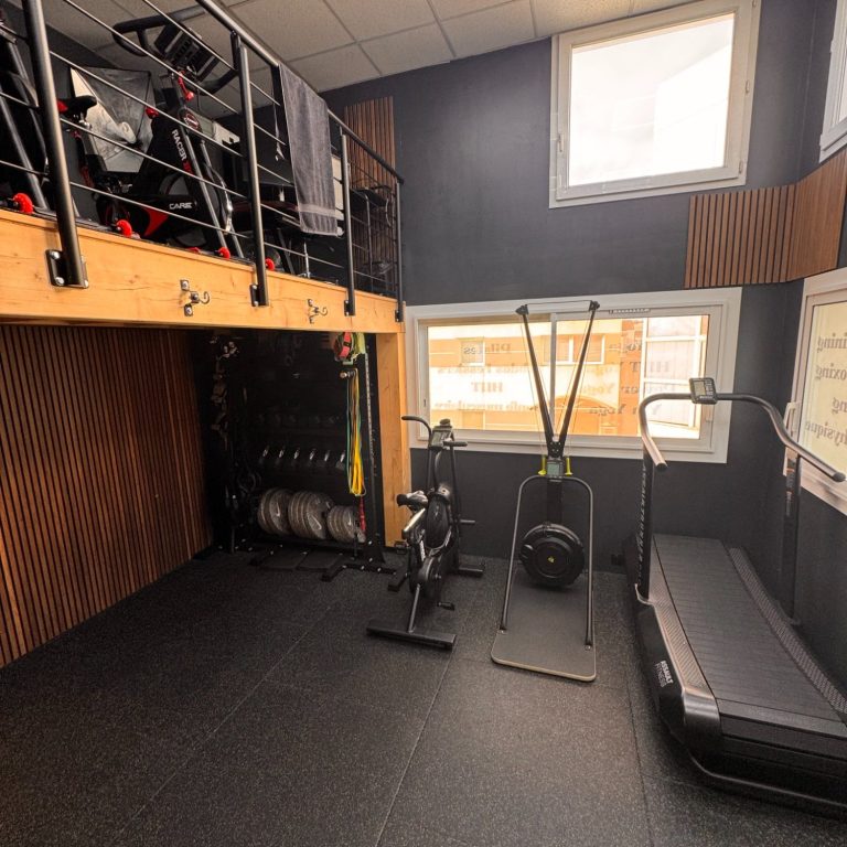 Salle de fitness avec équipements variés et espace surélevé.
