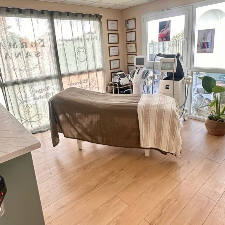 Cabine de soin spa avec lit, équipements esthétiques et plante en pot.